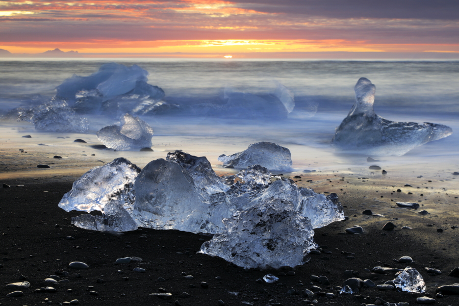 Vor Jahren reichte Europas mächtigster Gletscher Vatnajökull (Südost-Island) noch bis zum Meer, heute hat er sich bereits um 3 km zurückgezogen. An seinem Rande brechen ständig Eisblöcke ab und sammeln sich in der 18 km² großen und bis 248m tiefen Lagune Jökulsárlón. Kurz vor der Mündung in den Atlantik stauen sich die Eisblöcke bei Flut vor einer Engstelle, über die auch die Brücke der Ringstraße 1 führt. Mit einsetzender Ebbe wird das Eis ins Meer hinausgeschwemmt, um in vielen Bruchstücken beim nächsten Hochwasser an den Strand getrieben zu werden. Bis zur folgenden Ebbe sind die meisten Eisstücke geschmolzen.