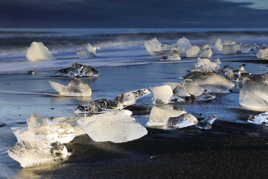 Vor Jahren reichte Europas mächtigster Gletscher Vatnajökull (Südost-Island) noch bis zum Meer, heute hat er sich bereits um 3 km zurückgezogen. An seinem Rande brechen ständig Eisblöcke ab und sammeln sich in der 18 km² großen und bis 248m tiefen Lagune Jökulsárlón. Kurz vor der Mündung in den Atlantik stauen sich die Eisblöcke bei Flut vor einer Engstelle, über die auch die Brücke der Ringstraße 1 führt. Mit einsetzender Ebbe wird das Eis ins Meer hinausgeschwemmt, um in vielen Bruchstücken beim nächsten Hochwasser an den Strand getrieben zu werden. Bis zur folgenden Ebbe sind die meisten Eisstücke geschmolzen.